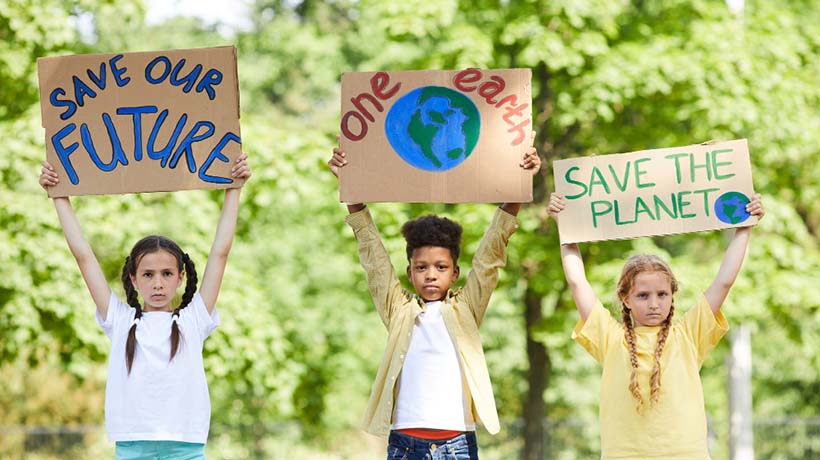 Three children holding signs for ecology
