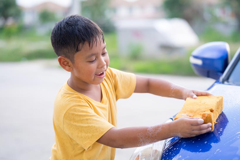 Un garçon lave une voiture