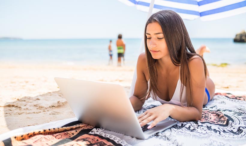 Une femme avec un ordinateur portable à la plage